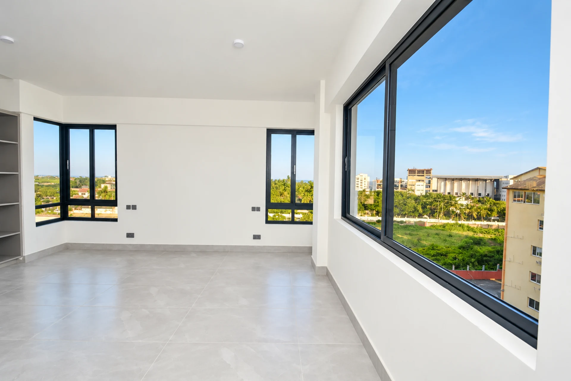A bedroom with a wide window over the neighbourhood