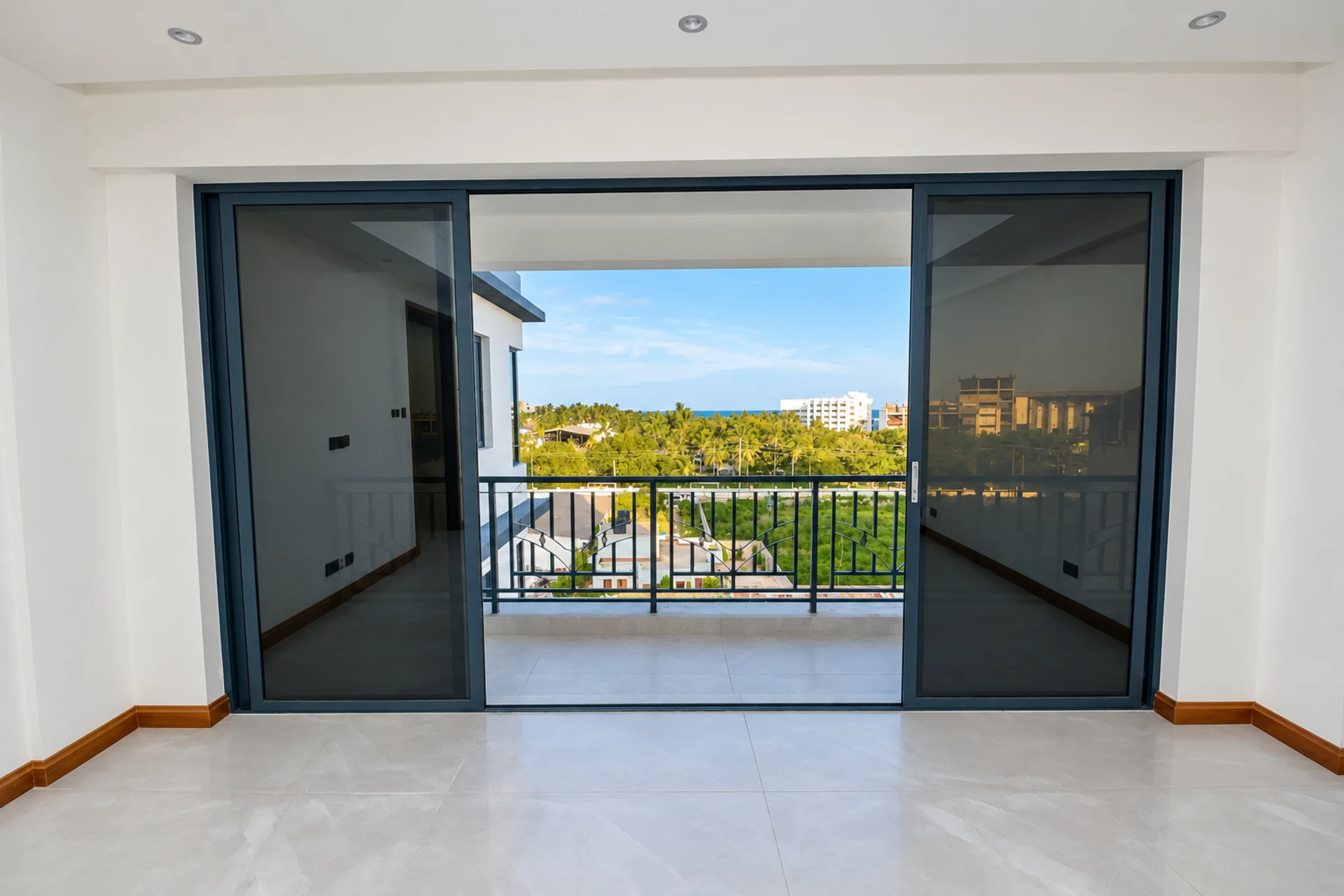 A living room opening through sliding doors onto a balcony with a sea view